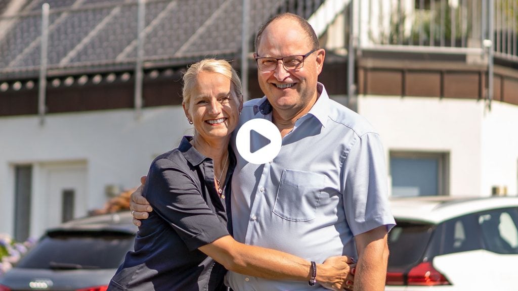 Herr Bruns und Ehefrau posieren vor ihrem Haus mit neuer Photovoltaikanlage